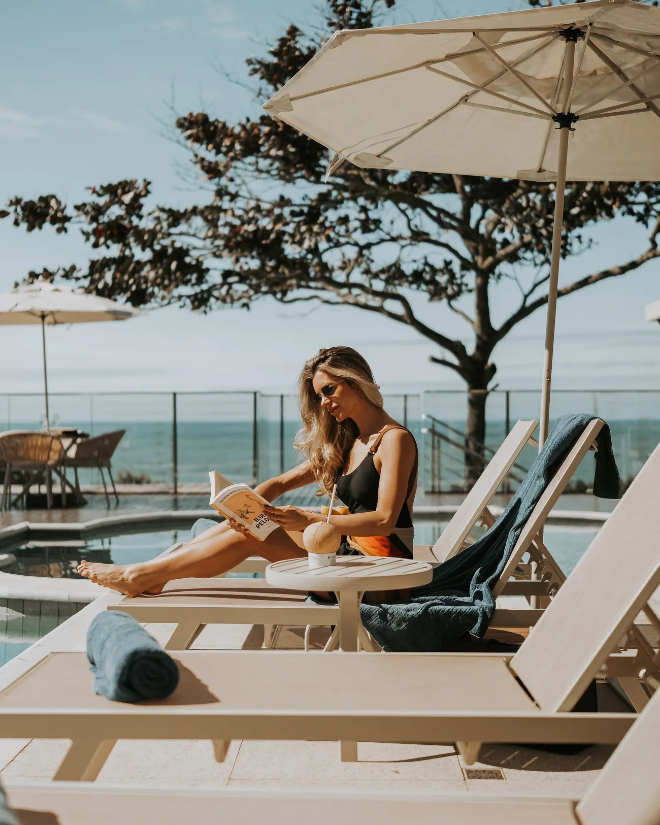 Leitura na espreguiçadeira, com a piscina e o mar atrás